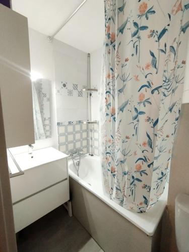 une salle de bain avec une baignoire, un lavabo et un rideau de douche dans l'établissement Appartement vue mer Le Barcarès, au Barcarès