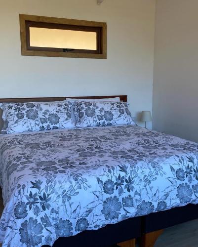 a bed in a bedroom with a blue floral bedspread at Cabaña La Quebrada Tunquen in Valparaíso