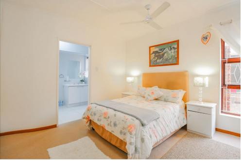 a white bedroom with a bed and a bathroom at 17 Villa Leadwood in Jeffreys Bay
