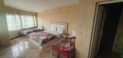 um quarto com duas camas e uma cadeira. em E & P Hotel 2 em Tetovo