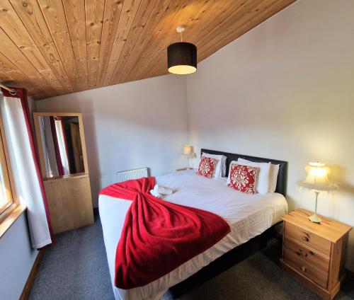 a bedroom with a bed with a red blanket on it at Cleish 7 With Private Hot Tub - Fife - Loch Leven - Lomond Hills - Pet Friendly in Kelty