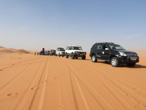 a line of vehicles parked in the desert at Merzouga Camel Trekking Camp in Merzouga