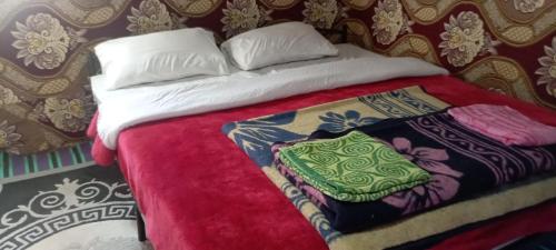a bed with a red blanket and a pillow at Merzouga Camel Trekking Camp in Merzouga