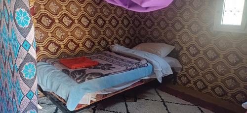a small bed in a room with a wall at Merzouga Camel Trekking Camp in Merzouga