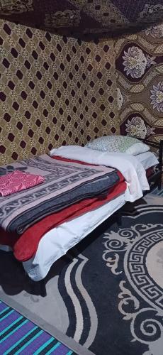 a bed sitting on top of a rug in a bedroom at Merzouga Camel Trekking Camp in Merzouga