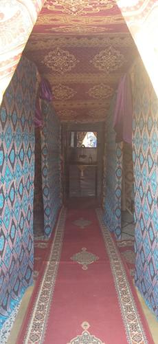 a room with a red and blue carpet and a table at Merzouga Camel Trekking Camp in Merzouga