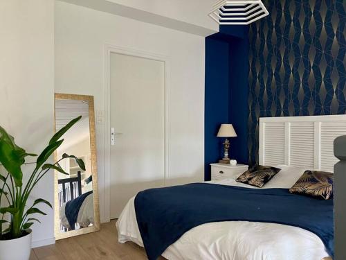 une chambre avec un lit avec un mur bleu dans l'établissement Appart vue port, proche océan, à Les Sables-dʼOlonne