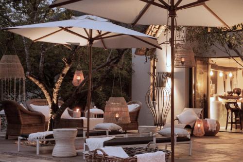 a patio with two umbrellas and chairs and tables at African Flair Boutique Safari Lodge in Hoedspruit
