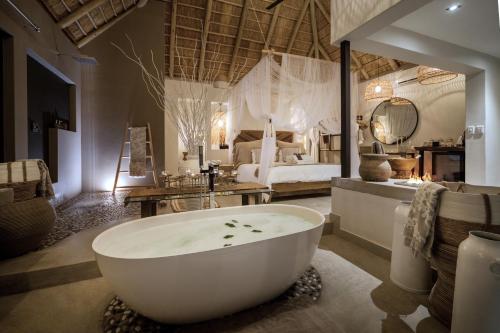 a bathroom with a bath tub and a bedroom at African Flair Boutique Safari Lodge in Hoedspruit