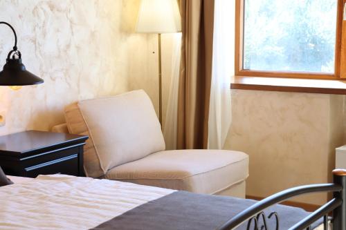 a bedroom with a chair and a bed and a window at Rustikalna soba sa kupaonicom Milena in Kaldir