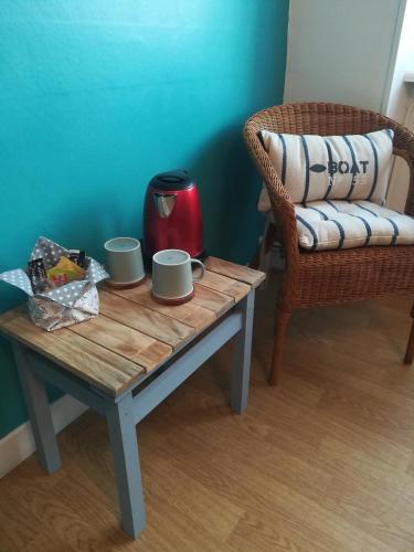 een salontafel met twee kopjes erop en een stoel bij Nouelig bras in Loctudy