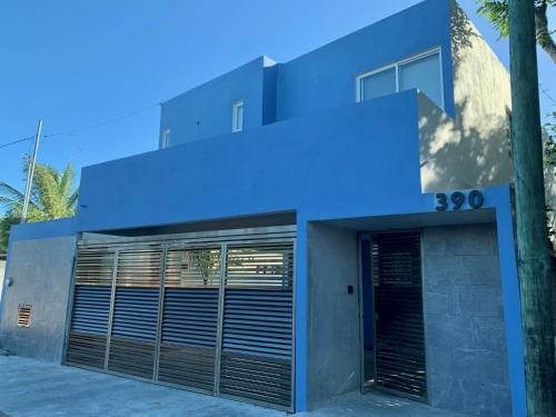 a blue building with a garage with a door at Departamento cocoonning en "Casa Livia" piscina y jardín in Mérida