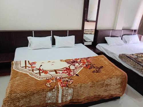 a bedroom with two beds and a table in the middle at Hotel Barsana Palace, Near Mahakal Temple- 200 meter in Ujjain