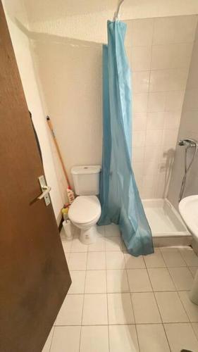 uma casa de banho com um WC e uma cortina de chuveiro azul em Studio centre-ville em Cluses
