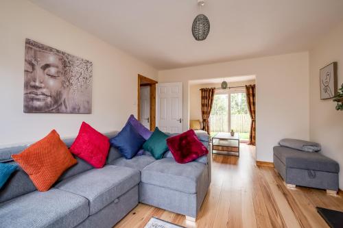a living room with a gray couch with colorful pillows at Stylish & spacious 3 bedroom entire house in Lisburn with parking in Lisburn