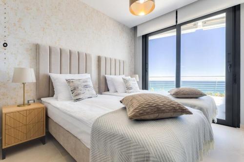 two beds in a bedroom with a view of the ocean at Apartament Infinity View in Arenales del Sol