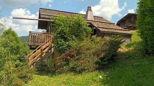 an old house with a wooden deck in the grass at LA GODILLE in La Clusaz