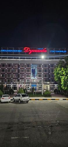 een hotel met auto's die 's nachts op een parkeerplaats geparkeerd staan bij Dushanbe Hotel in Doesjanbe