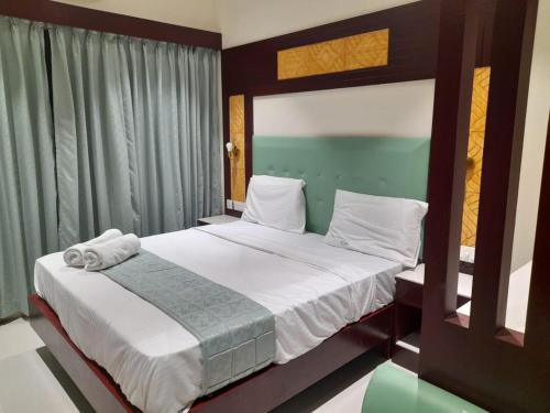 um quarto com uma cama grande e lençóis brancos em Hotel Harshanaa Elite em Kanyakumari
