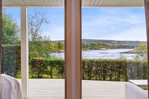 a room with a glass door looking out at a lake at Glomma House in Kongsvinger