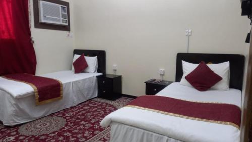 um quarto de hotel com duas camas com almofadas vermelhas em العييري للشقق المفروشة النعيريه 4 em Al Nairyah