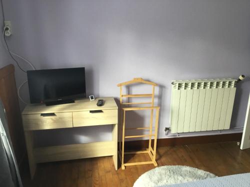 a room with a tv and a desk with a television and a radiator at Logement avec parking max 7 personnes in Eauze