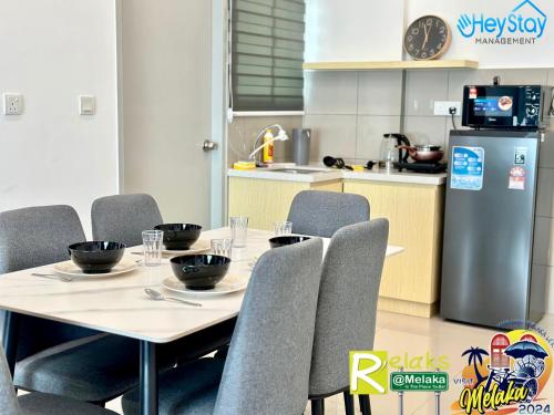 a dining room with a table and chairs and a kitchen at Amber Cove Impression City By Heystay Management in Melaka
