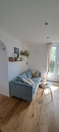 ein Wohnzimmer mit einem blauen Sofa auf einem Holzboden in der Unterkunft Charming appartment near public transport in Suresnes