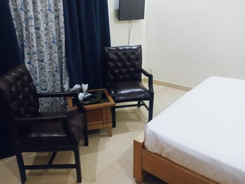 - deux chaises et un lit dans une chambre d'hôtel dans l'établissement Home Inn Guesthouse, à Islamabad