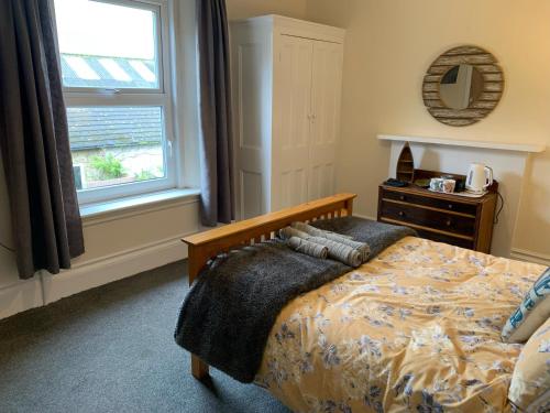 a bedroom with a bed with a dresser and a window at Peaceful garden view double with ensuite in house opposite beach, with access to private garden and bike store in Kent