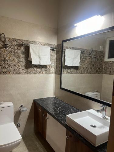 a bathroom with a sink and a mirror and a toilet at Luxury apartment near expo in Greater Noida