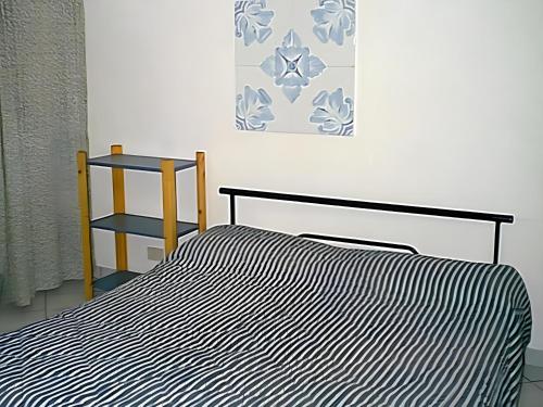 a bed with a black and white striped blanket next to a chair at L'Isolana Case Vacanza Alloro 3 in Ponza