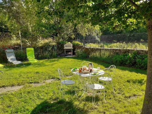 une table et des chaises dans l'herbe dans une cour dans l'établissement La Calmille Maison avec Jardin, à Les Salelles