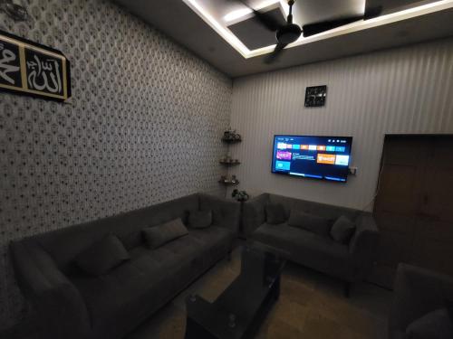 a living room with a couch and a flat screen tv at Harrys Guest House in Gujrānwāla