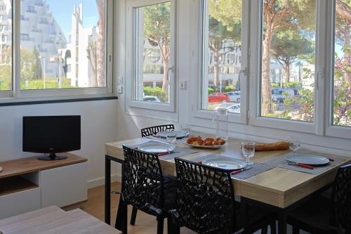 une salle à manger avec une table, des chaises et des fenêtres dans l'établissement Studio tout équipé vue sur Port, à La Grande Motte