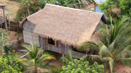 una casa antigua con techo de paja y palmeras en OBT - The Coconut Bungalow 