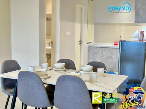 a table with chairs and cups and bowls on it at The Apple Residence By Heystay Management in Melaka