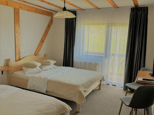 a bedroom with two beds and a window at Pensiunea Ursul Carcotas in Fundata