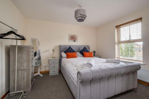 a bedroom with a large bed with orange pillows at Stylish & spacious 3 bedroom entire house in Lisburn with parking in Lisburn