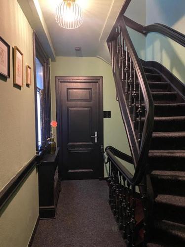 a hallway with a black door and a staircase at SeventyFive in Amsterdam