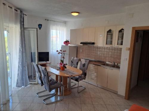 a kitchen with a wooden table and chairs in a room at Apartmani Mila-Casa Bianca in Medulin