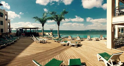 una terraza de madera con tumbonas y el océano en المثالي, en Bayt Mi‘yād