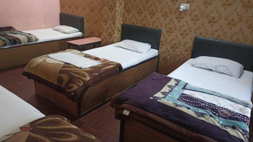 a room with three beds in a room at Hotel Opera in Bharatpur