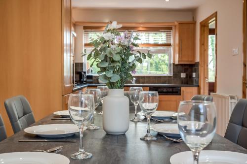 a table with glasses and a vase with flowers on it at Stylish & spacious 3 bedroom entire house in Lisburn with parking in Lisburn