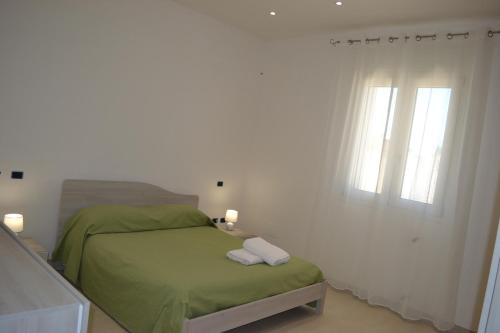 una camera con un letto verde e due finestre di Villa Serena a Bagnolo del Salento