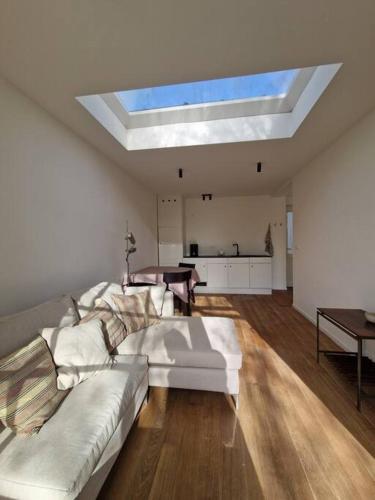 a living room with a white couch and a skylight at Tiny house in Antwerp
