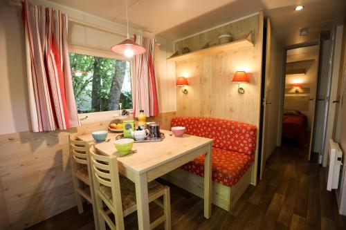 - une salle à manger avec une table et un canapé rouge dans l'établissement Camping Les Cruses, à Ribes