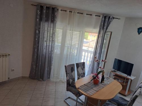 a living room with a table and chairs and a television at Apartmani Mila-Casa Bianca in Medulin