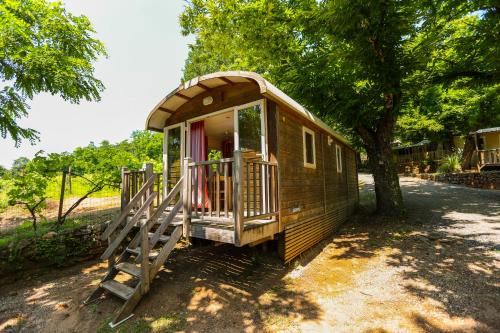 una pequeña casa con un porche y un árbol en Camping Les Cruses, en Ribes