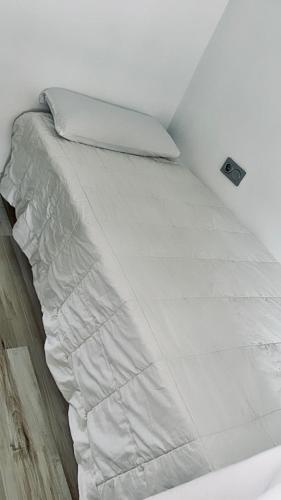 a bed with white sheets and a pillow at Piso reformado en Murcia con terraza in Murcia